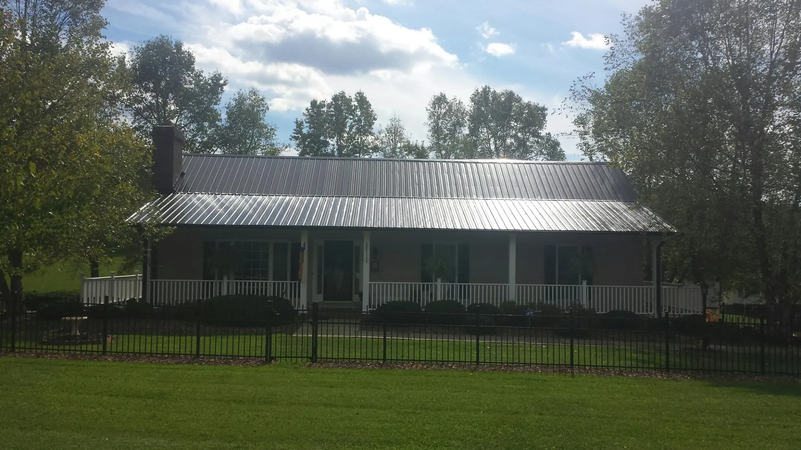 Gray metal roof on a brick ranch with a full width front porch — Gutter Guard Installation work by our crew in University Park